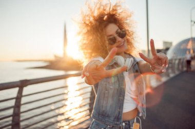 Gür saçlı genç şık kadın göstermek zafer işareti