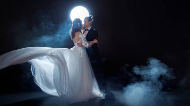 Gizemli ve romantik bir buluşma, Gelin ve damat ayın altında. Birlikte sarılmak. Erkek ve kadın, gelinlik.