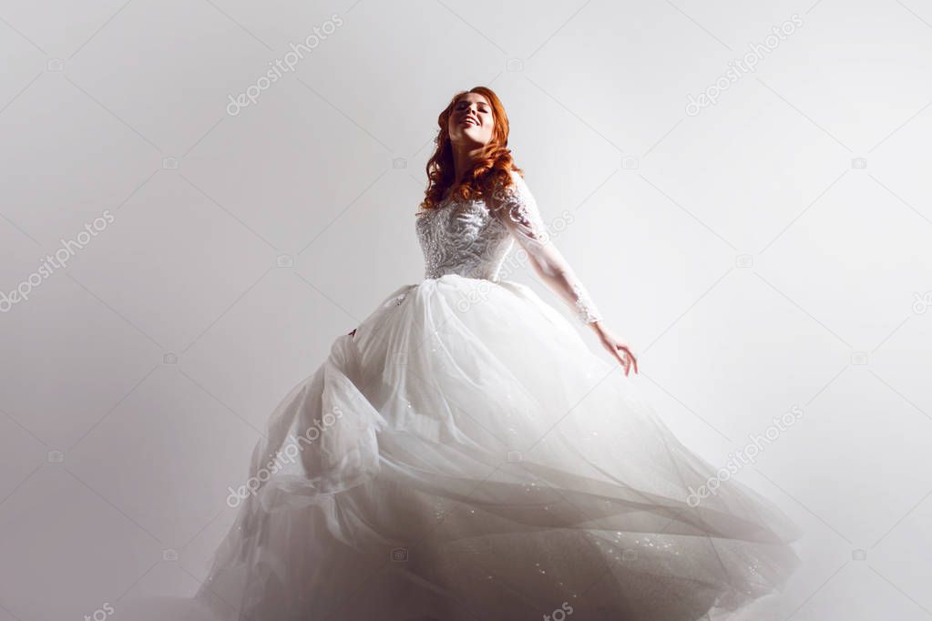 Lovely young woman bride in a lavish wedding dress. Charming bride on Light background with a shadow