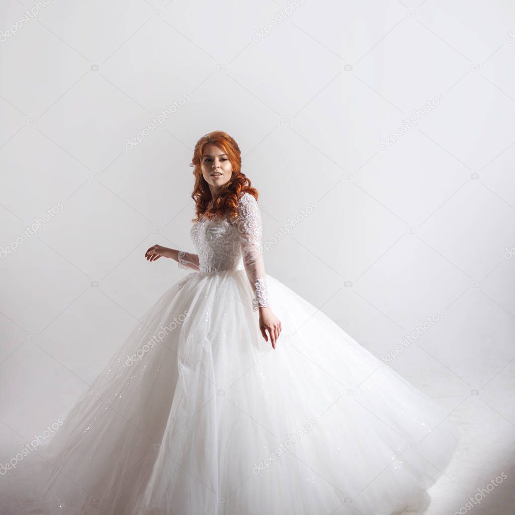 Lovely young woman bride in a lavish wedding dress. Light background.