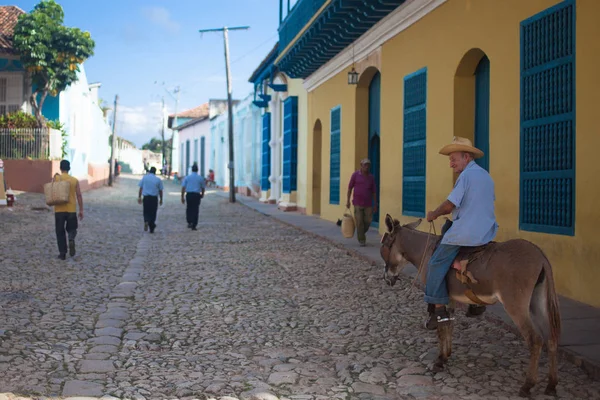 TRINIDAD, CUBA - NOVEMBER 9, 2012: Old man in the hat riding a donkey on the street