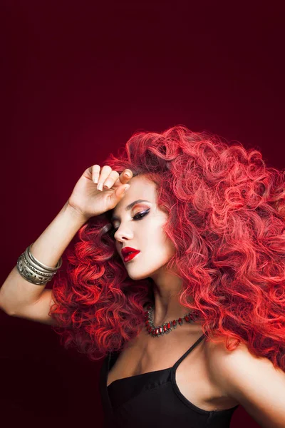 Portré, fiatal, vonzó nő, nagyon buja frizura. Vörös hajú, piros háttéren. — Stock Fotó