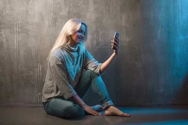 Egy fiatal nő használ egy okostelefon, kék alakformálás — Stock Fotó