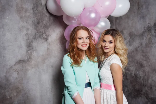 Blonde en roodharige. Twee jonge charmante vriendinnen op het feest. Gelukkig en vrolijk meisje met ballonnen. — Stockfoto