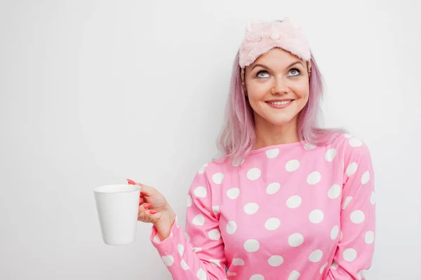 Feliz joven beba café de la mañana. Hermosa chica en pijama rosa y máscara para dormir — Foto de Stock