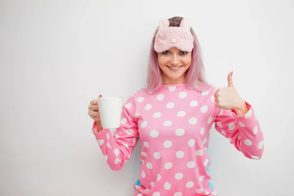 Feliz joven beba café de la mañana. Hermosa chica en pijama rosa y máscara para dormir —  Fotos de Stock