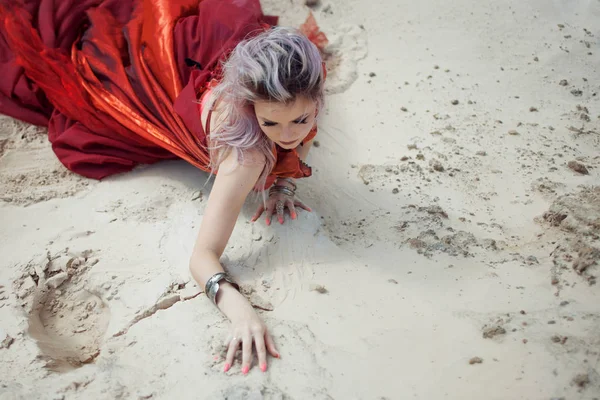 Oriental dance. Beautiful woman sitting on the sand, hands with bracelets on sand.