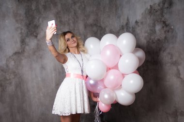 Pembe balonlu beyaz elbiseli Genç sarışın sevimli bir selfie yapmak