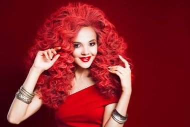 Toplam kırmızı tarzı gülümseyen genç kadın. Kıvırcık kırmızı saçlı kız portresi