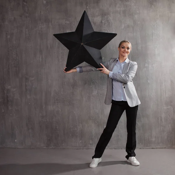 Be a star. A young woman in a business suit with a big black star in hand — Stock Photo, Image