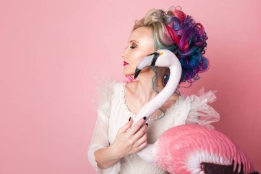 Renkli saç ile şık ve güzel bir kadın. Bir pembe Flamingo rakam sarılma.