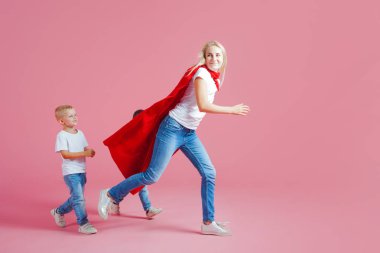Mom is a superhero. Fun family, a young blond woman in a red Cape and her son. Sons follow mom clipart