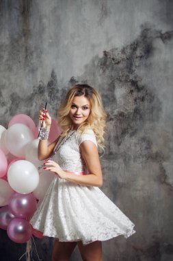 Genç kadın dans ve soda içme. Güzel bir çekici sarışın portresi ile bir şişe içki ve balonlar