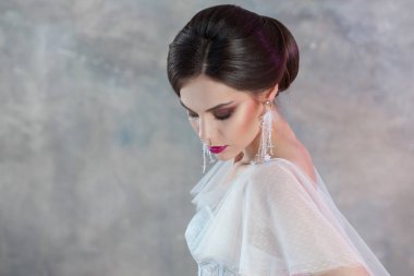 Şık bir saç modeli ile genç zarif esmer gelin portresi.