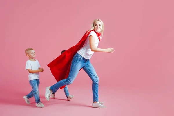 Мама супергерой. Веселая семья, молодая блондинка в красном плаще и ее сын. Сыновья следуют за мамой — стоковое фото