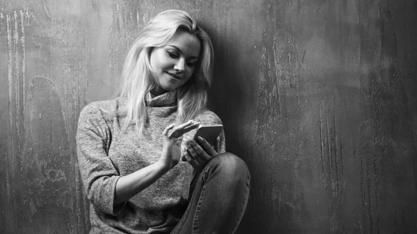 Une jeune femme utilise un smartphone, assise sur le sol et regardant l'écran du smartphone, utilise Internet — Photo