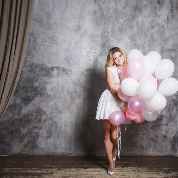 Jovem loira encantadora em um vestido branco com balões rosa, na festa . — Fotografia de Stock