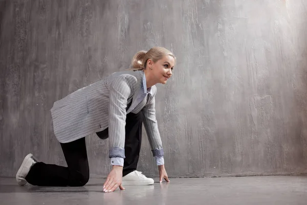Young woman in business suit and sneakers. At a low start, ready to run a long distance Stock Photo