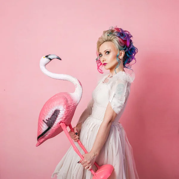 Mujer elegante y hermosa con el pelo de color. Abrazar una figura de Flamingo rosa . —  Fotos de Stock