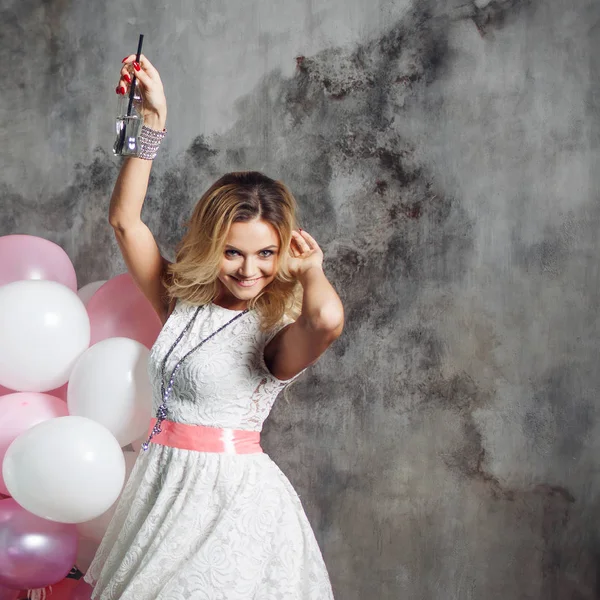 Jonge vrouw dansen en het drinken van frisdrank. Portret van een mooie glamoureuze blonde, met een fles drank en ballonnen — Stockfoto