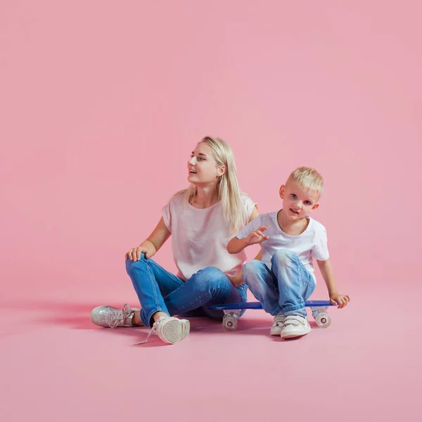 Uma jovem mãe positiva com um filho pequeno. Linda loira com seu bebê em um skate — Fotografia de Stock