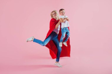 Süper anne. Eğlenceli aile, kırmızı pelerin ve oğlu genç sarışın bir kadın atlar ve kapalı alır