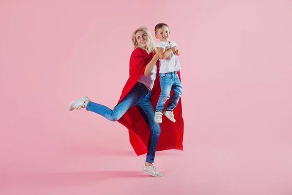 Super mamma. Divertente famiglia, una giovane donna bionda in un Capo rosso e suo figlio salta e decolla — Foto Stock