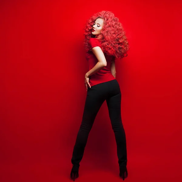 Porträtt av vacker ung kvinna med rött hår på röd bakgrund — Stockfoto