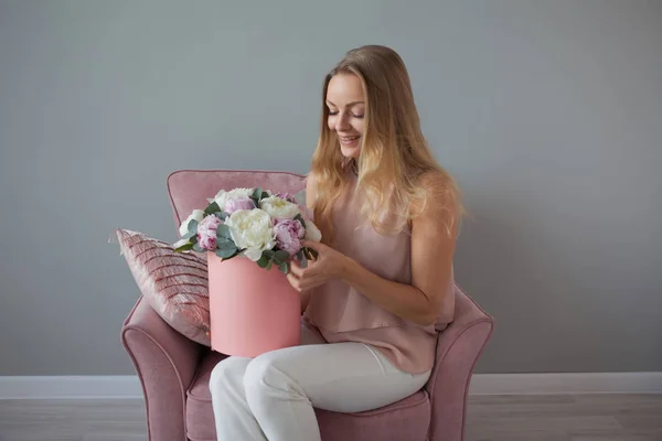 Happy blonde woman with flowers in a hat box. Bouquet of peonies. Girl with a pink bouquet of peonies — Stock Photo, Image