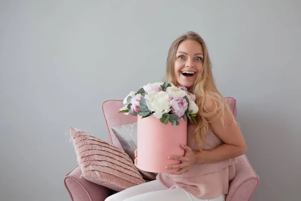 Happy blonde woman with flowers in a hat box. Bouquet of peonies. Girl with a pink bouquet of peonies — Stock Photo, Image