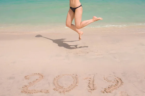 2019 Nieuwjaar in het zuiden, de zee. Branding van de zee. Blauwe golf komt aan de wal. Inscriptie op zand en vrouwen benen — Stockfoto