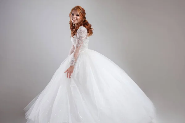 Glücklich lachende junge Frau im Hochzeitskleid. charmante Braut auf hellem Hintergrund. — Stockfoto