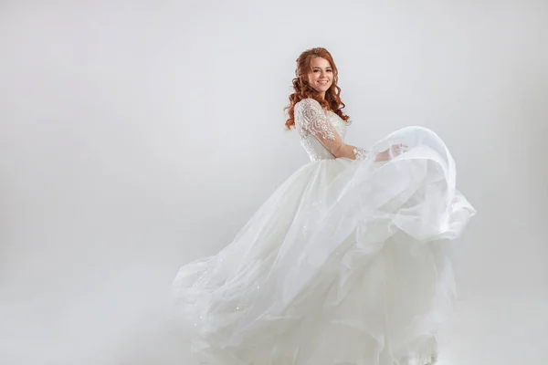 Delightful red-haired bride in a luxurious dress. Light background. — Stock Photo, Image