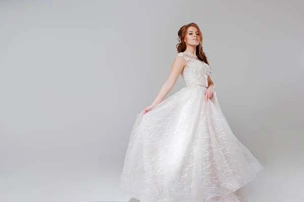 Krásná mladá žena nevěsta v opulentní svatební šaty. Světlé pozadí. — Stock fotografie