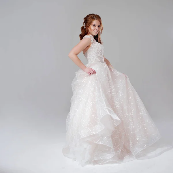 Krásná mladá žena nevěsta v opulentní svatební šaty. Světlé pozadí. — Stock fotografie