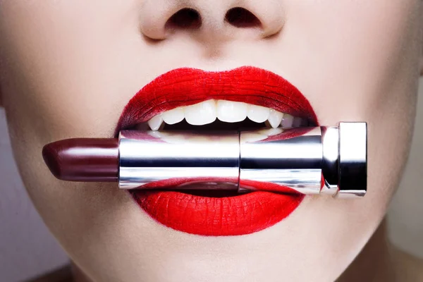 Hermosos labios de mujer, maquillaje brillante y elegante. lápiz labial palo en los dientes, concepto de moda — Foto de Stock