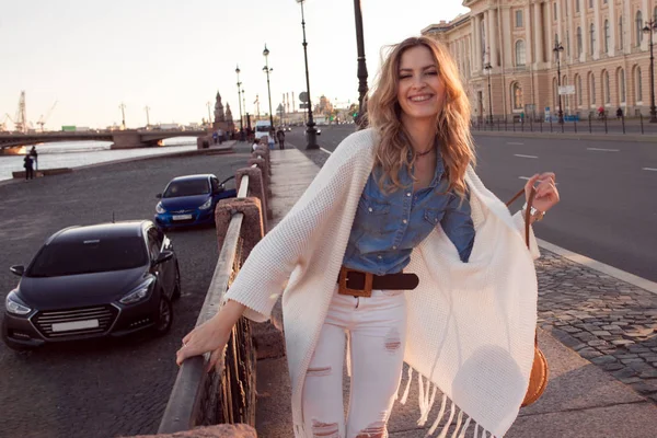 Retrato de uma mulher sorridente num casaco branco. Rindo menina no fundo da rua — Fotografia de Stock