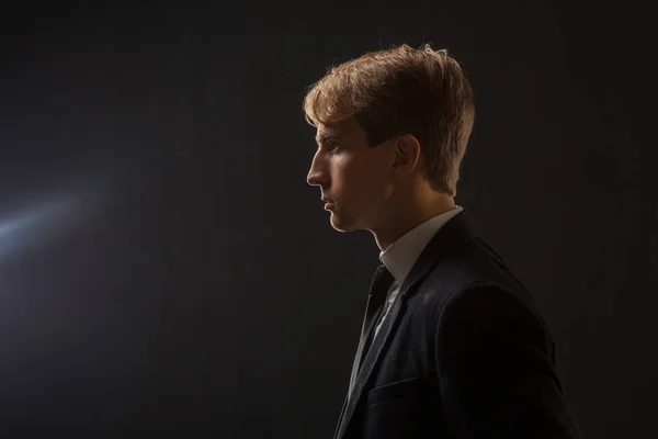 Profile of a young man in a business suit on a black background. — Stock Photo, Image