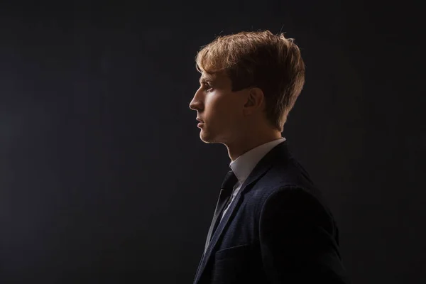 Profil av en ung man i kostym på svart bakgrund. — Stockfoto