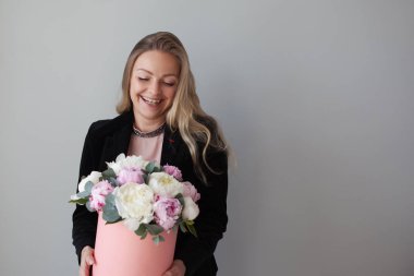 Sevimli sarışın kadın bir şapka kutusunda çiçekli. Peonies buket. Kız, iş tarzında çiçekler alır veya verir