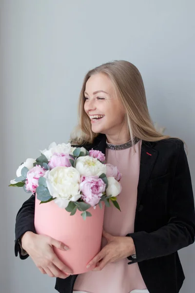 Charming blonde woman with flowers in a hat box. Bouquet of peonies. Girl in business style, receives flowers or gives — Stock Photo, Image