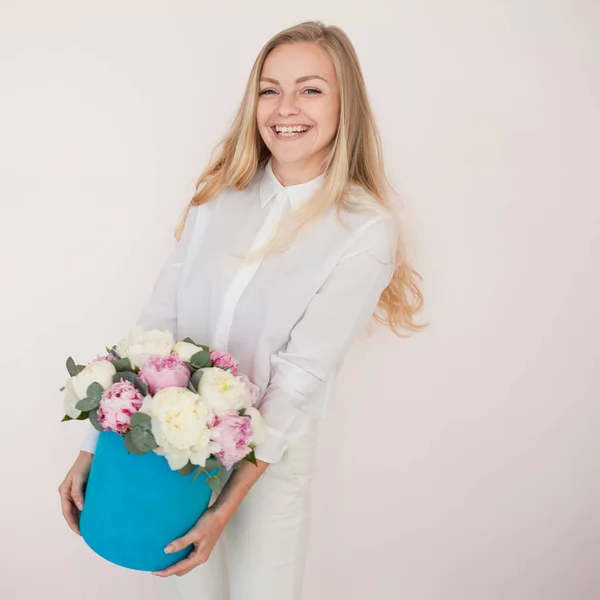 Woman with flowers in a hat box. Bouquet of peonies. Girl in business style, receives flowers or gives, Blue box. — Stock Photo, Image