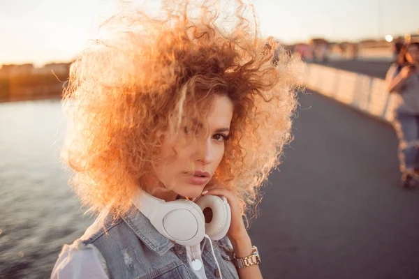 Chica de moda con auriculares grandes en un paseo por la ciudad, de cerca — Foto de Stock