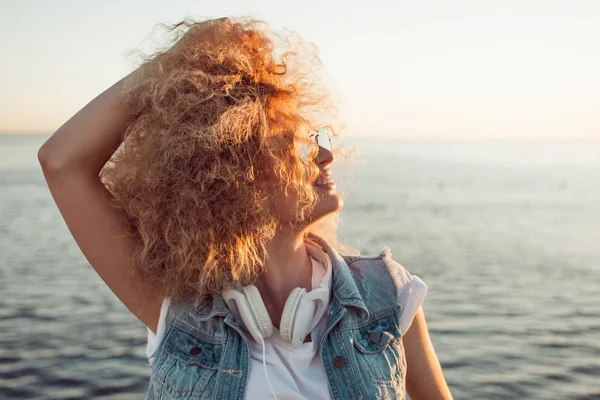 Chica de moda con auriculares grandes y gafas de sol en un paseo por la ciudad, de cerca —  Fotos de Stock