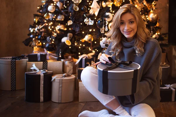 Belle jeune blonde avec des boîtes cadeaux sous le sapin de Noël — Photo