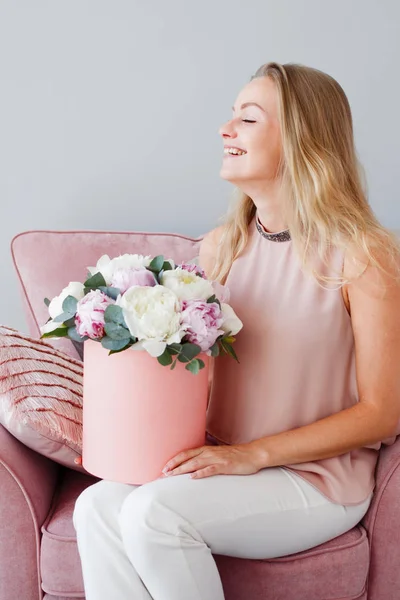 Mujer rubia feliz con flores en una caja de sombreros. Ramo de peonías. Chica con un ramo rosa de peonías — Foto de Stock