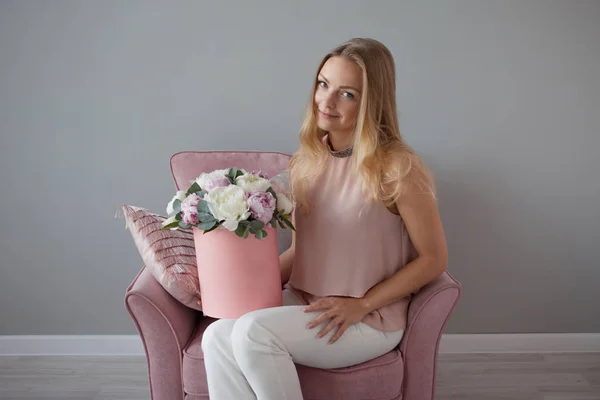 Happy blonde woman with flowers in a hat box. Bouquet of peonies. Girl with a pink bouquet of peonies — Stock Photo, Image