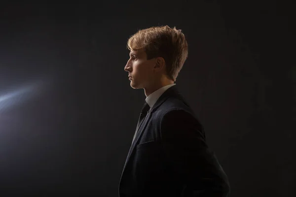 Profile of a young man in a business suit on a black background. — Stock Photo, Image
