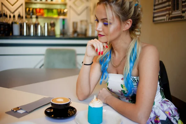 トレンディな女の子明るい色の髪、カフェに座って、コーヒーを飲み、デザートを食べる — ストック写真