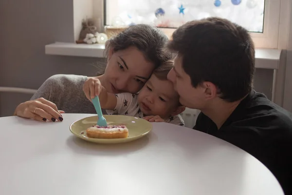 Feliz familia multiétnica. Mamá y papá le compran un pastel al niño. — Foto de Stock